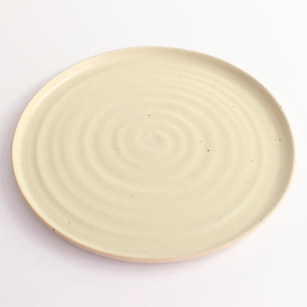 Above view of yellow glazed and flecked stoneware of plate