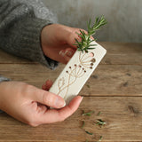 Front view of herbs being stripped through marker holes