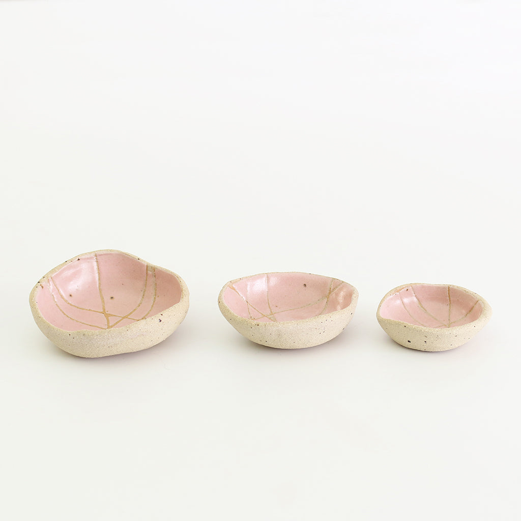 Row of three pink patterned wonky bowls in medium, small and mini sizes
