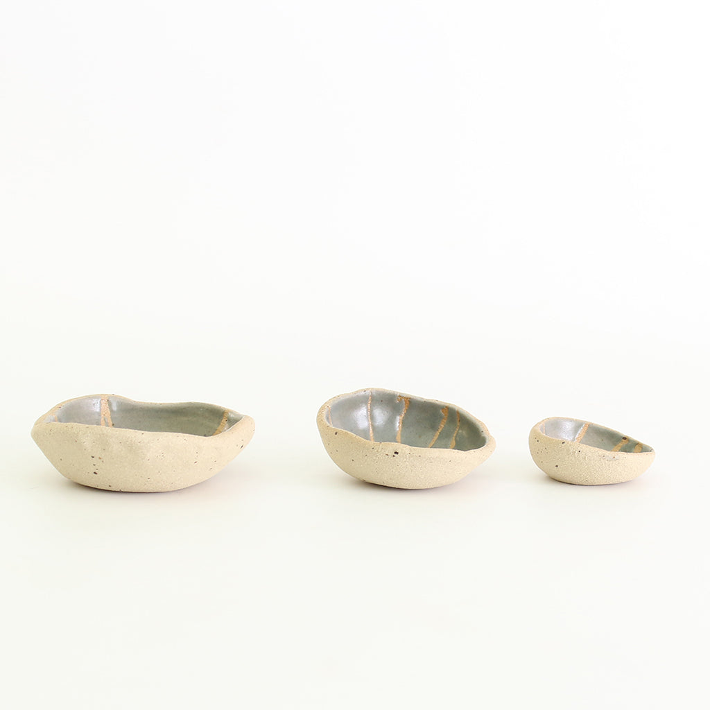 Row of three grey patterned wonky bowls in medium, small and mini sizes