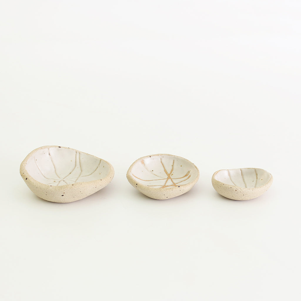 Row of three white patterned wonky bowls in medium, small and mini sizes
