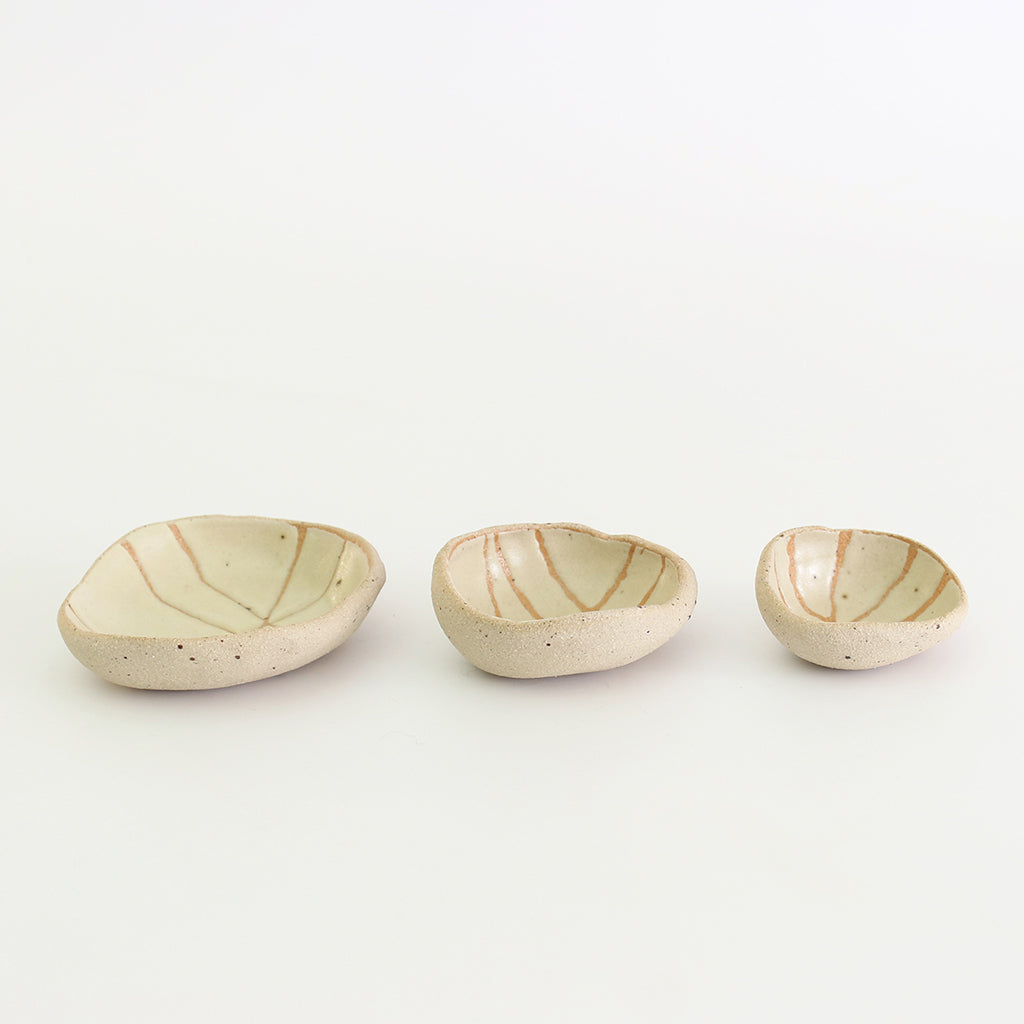 Row of three yellow patterned wonky bowls in medium, small and mini sizes
