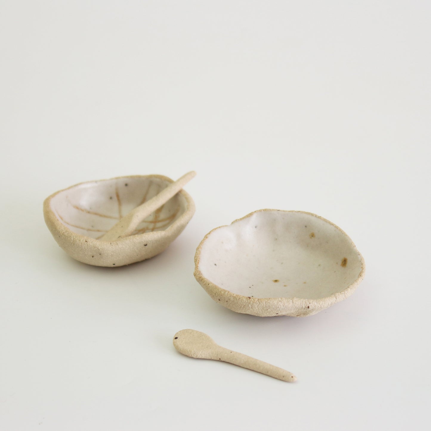 one patterned and one plain white mini bowl with clay spoons