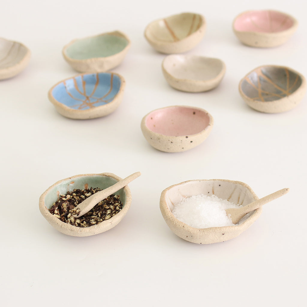 Mini wonky bowls, one with pepper granuals and one with salt and wonky spoons