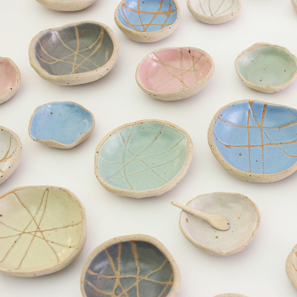 Patterned and plain wonky bowls in all sizes and colours, one with mini spoon