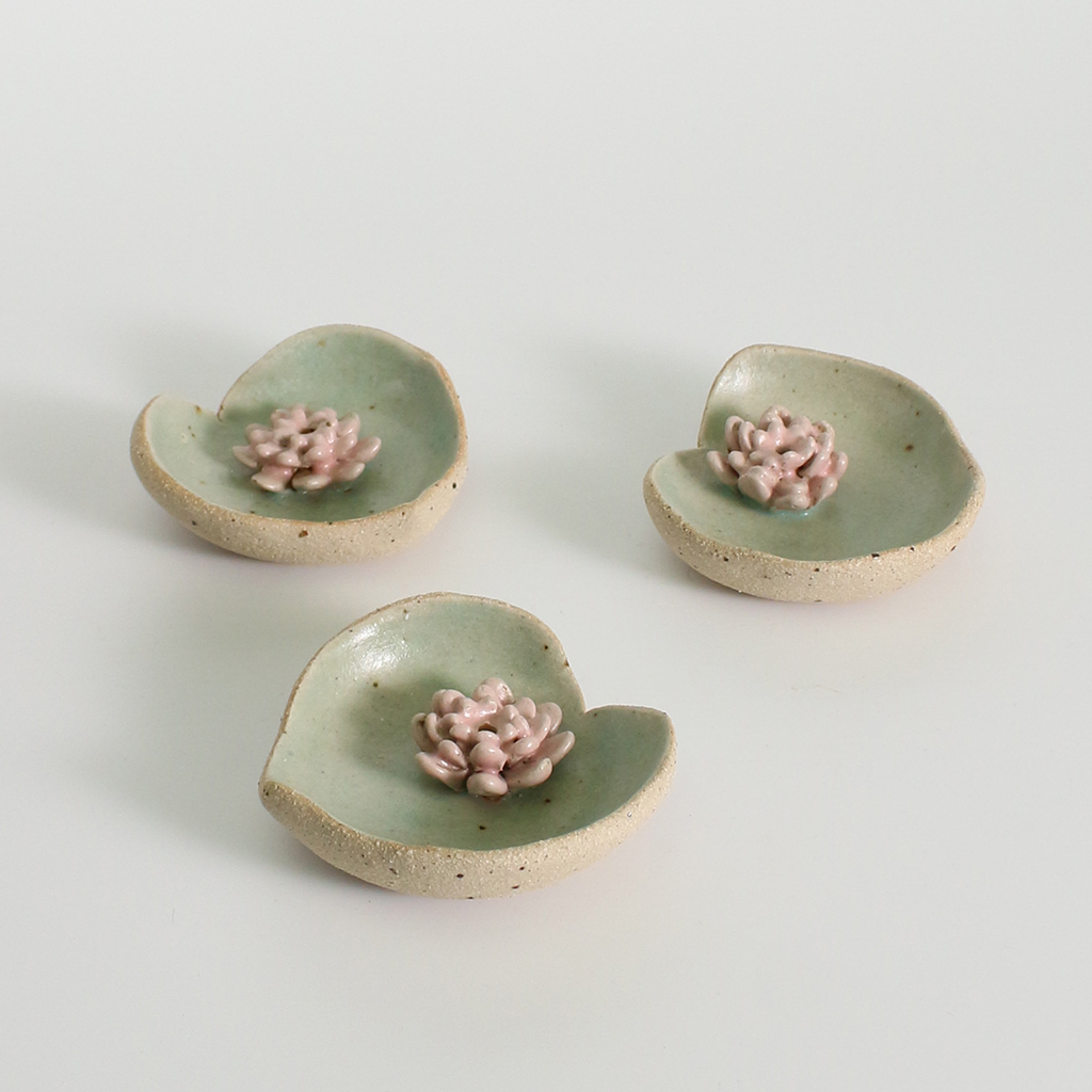 Three small ceramic dishes with pink floral arrangements on a light grey background