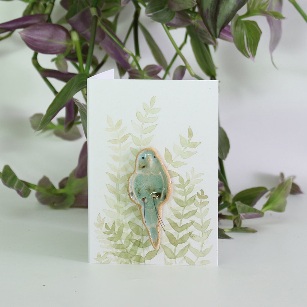 small ceramic and glass budgie plant decoration, on giftcard with watercolour leaves