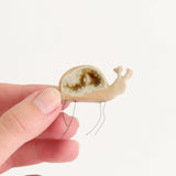 hand holding small ceramic and glass snail plant hugger