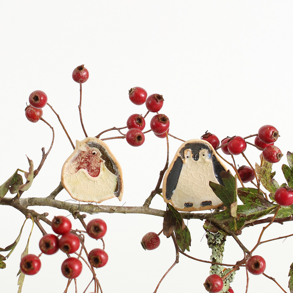 ceramic robin and ceramic penguin plant huggers on a branch