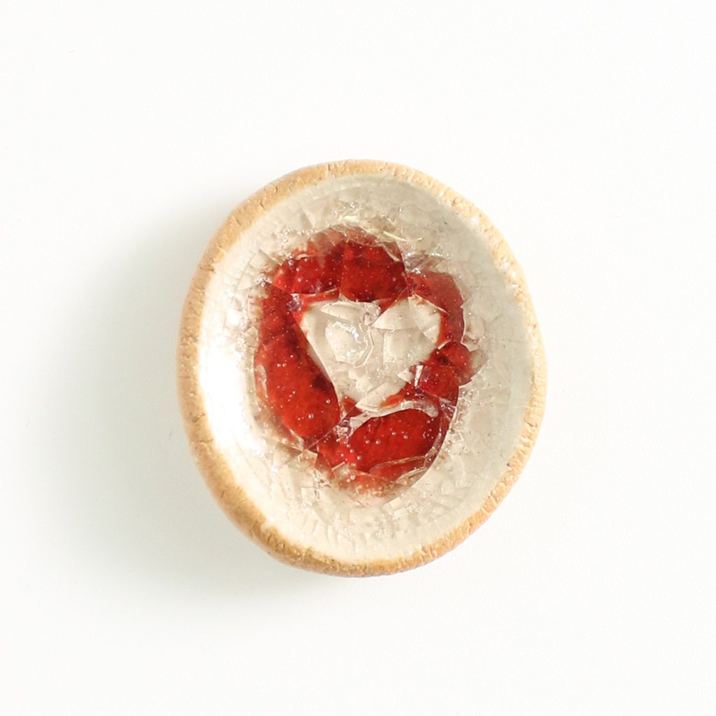 Small round worry stone with a red and white pattern on a white background