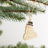 Ceramic snowman ornament hanging on a Christmas tree branch.