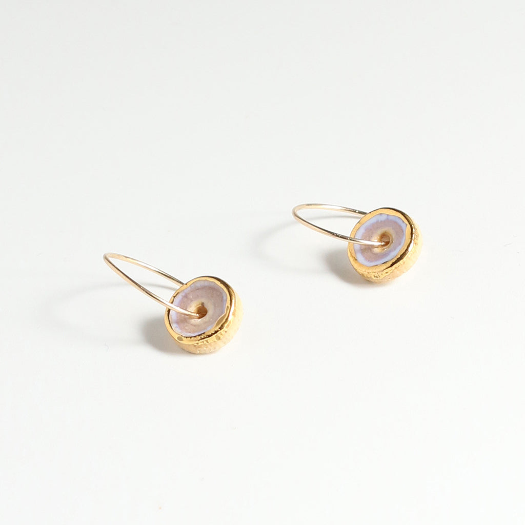 Pair of gold and pink earrings with circular designs on a light grey background
