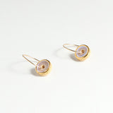 Pair of gold and pink earrings with circular designs on a light grey background