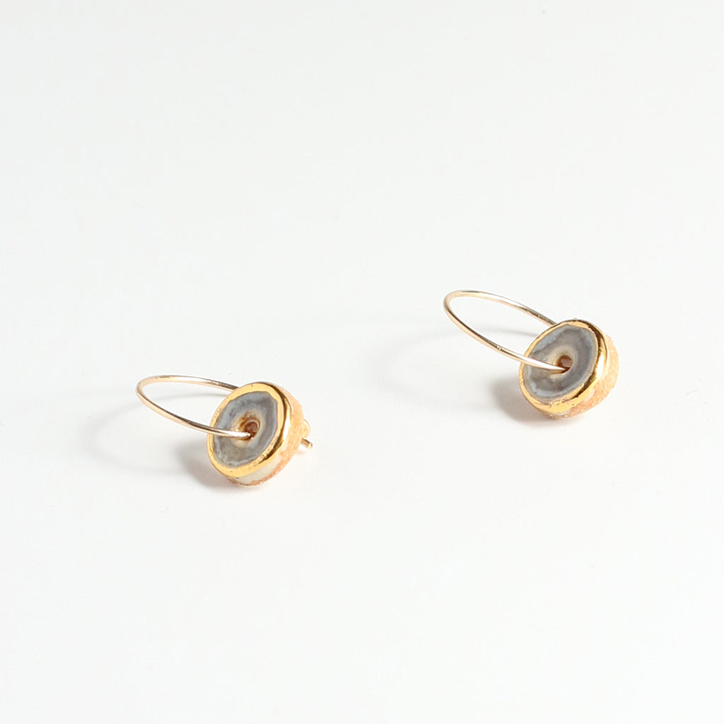 Pair of gold earrings with purple circular discs on a white background