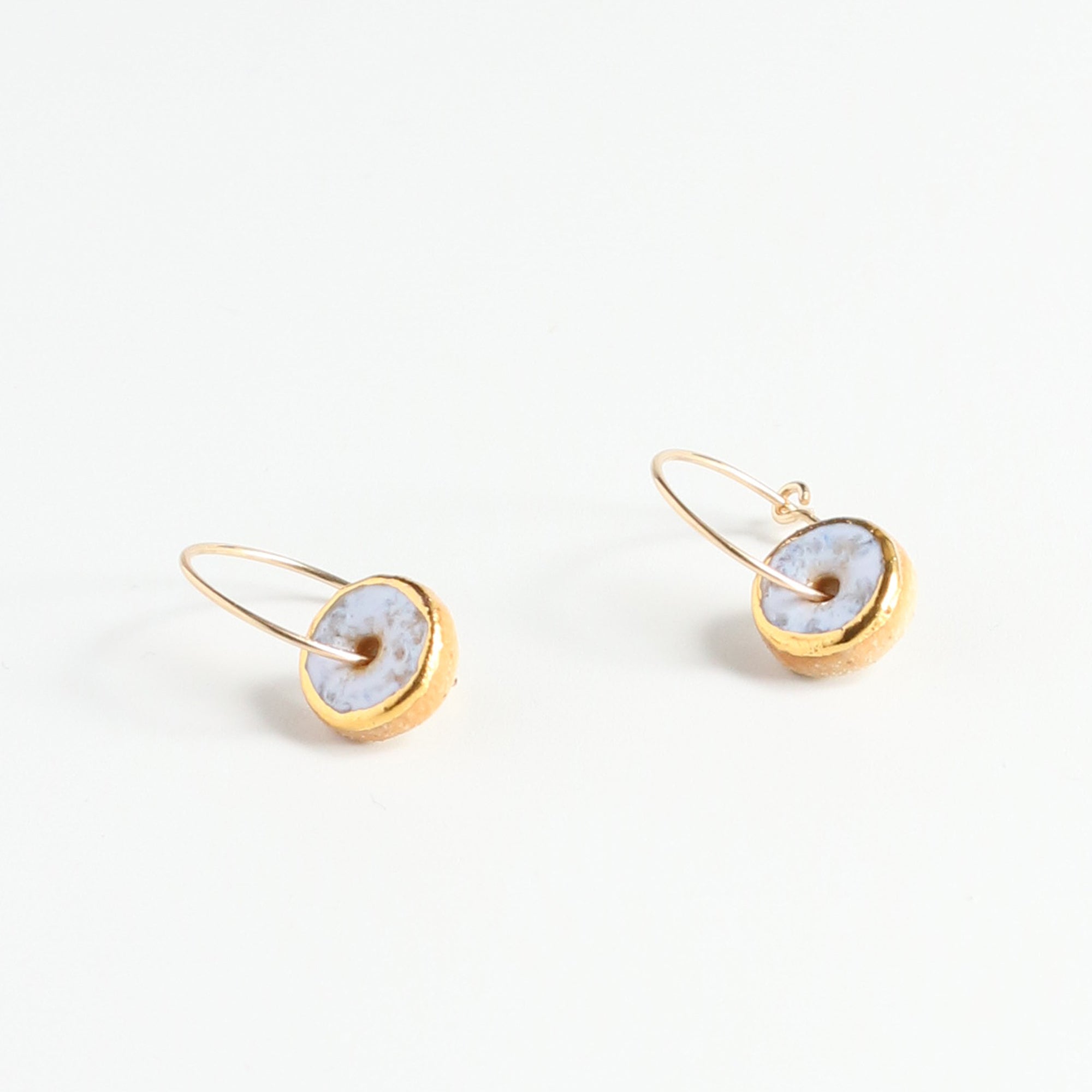 Gold hoop earrings with light opal circular stones on a white background