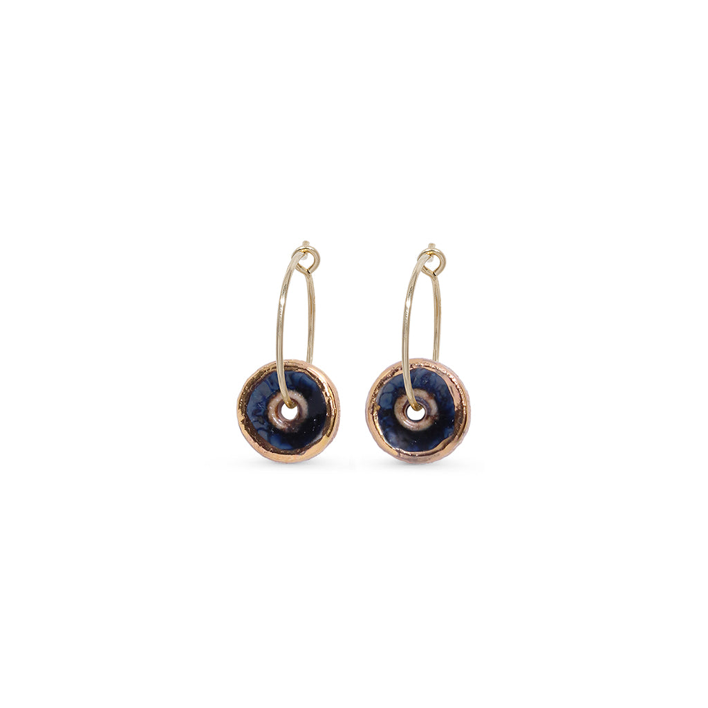 Pair of earrings with gold loops and black circular stones on a white background
