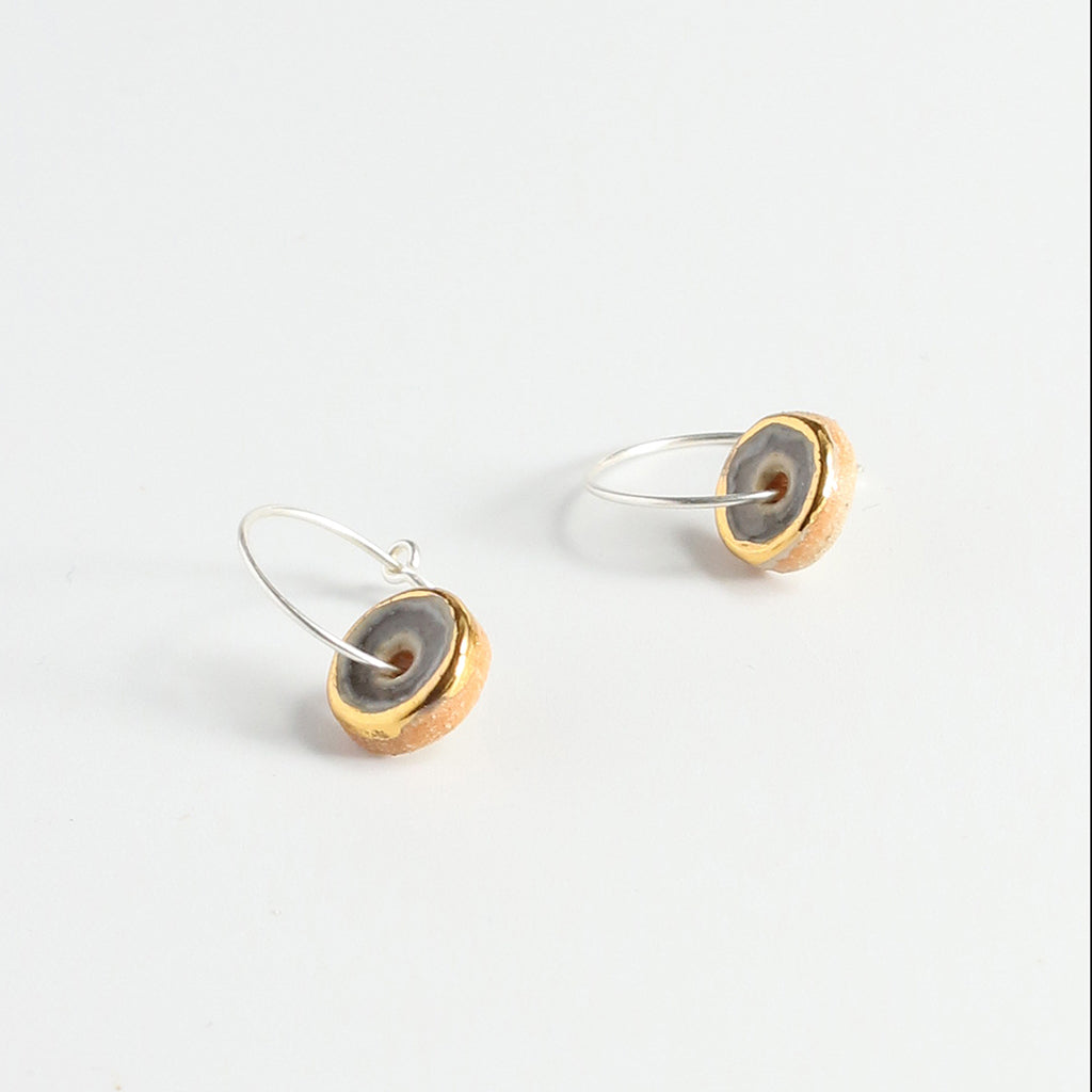 Pair of earrings with purple, gold and silver finishes on a white background
