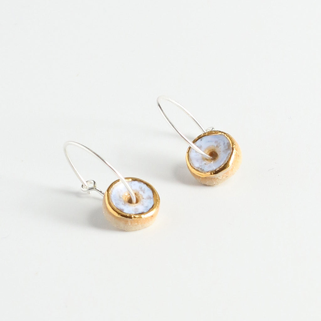 Pair of earrings with gold and opal circular designs on a light grey background