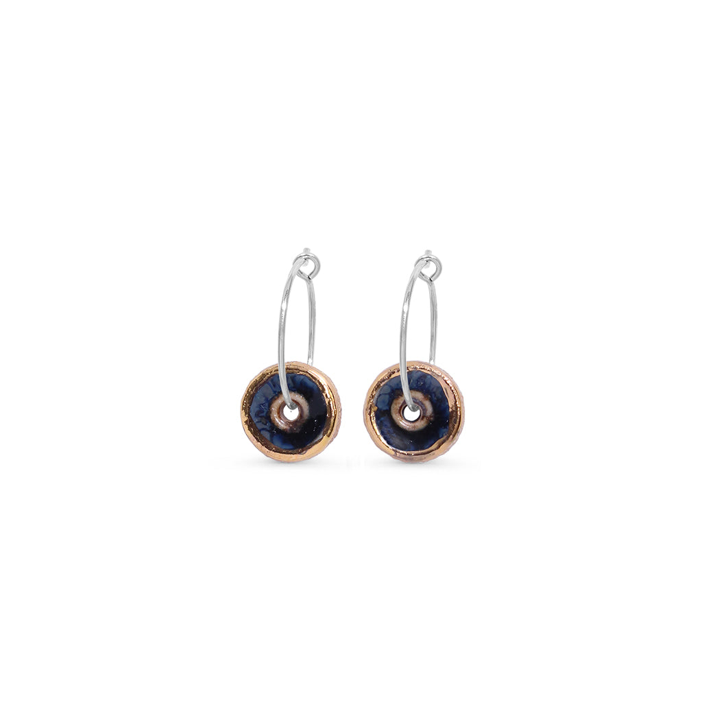 Pair of earrings with blue black circular designs with gold lustre outer on a white background