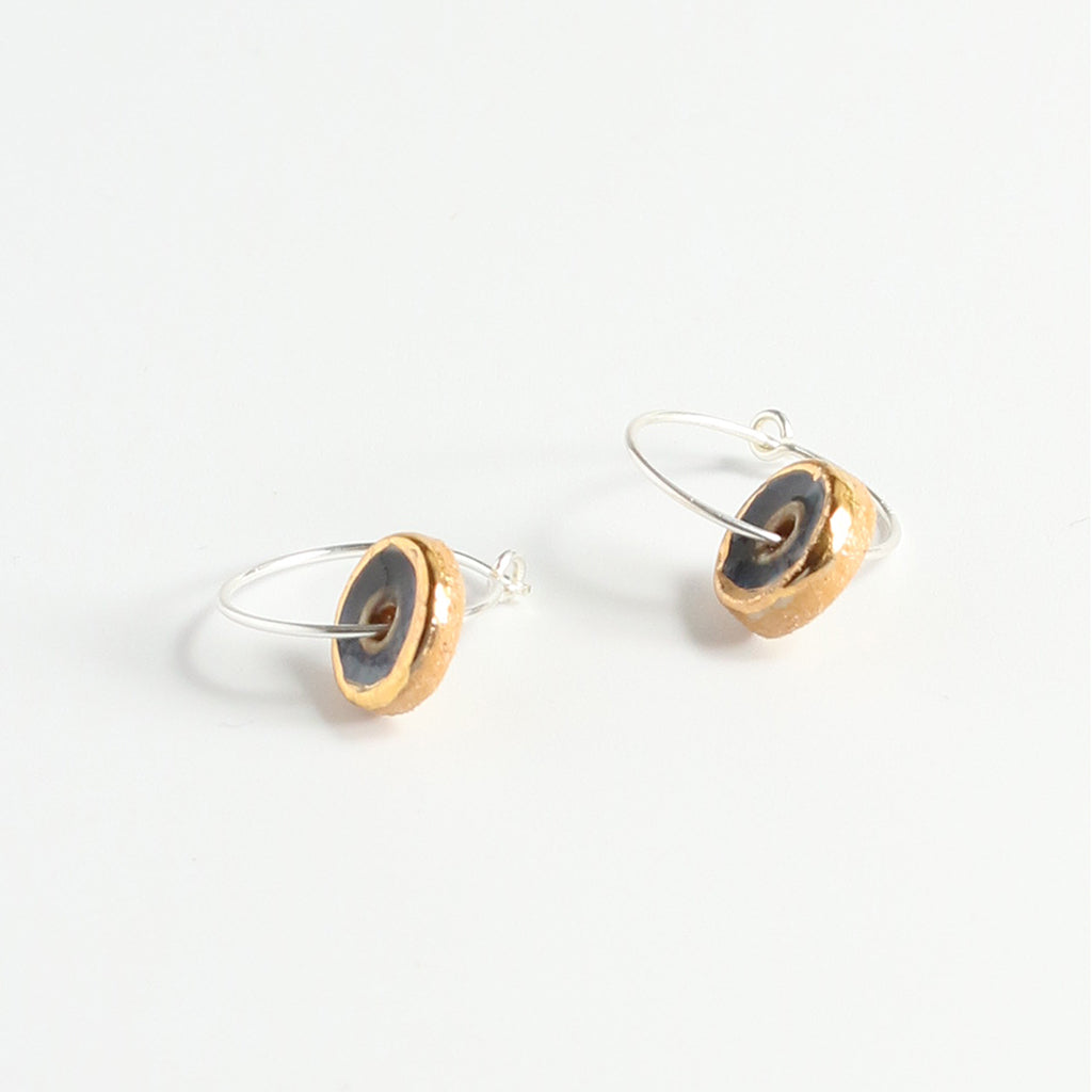 Pair of earrings with gold and black blue circular designs on a white background