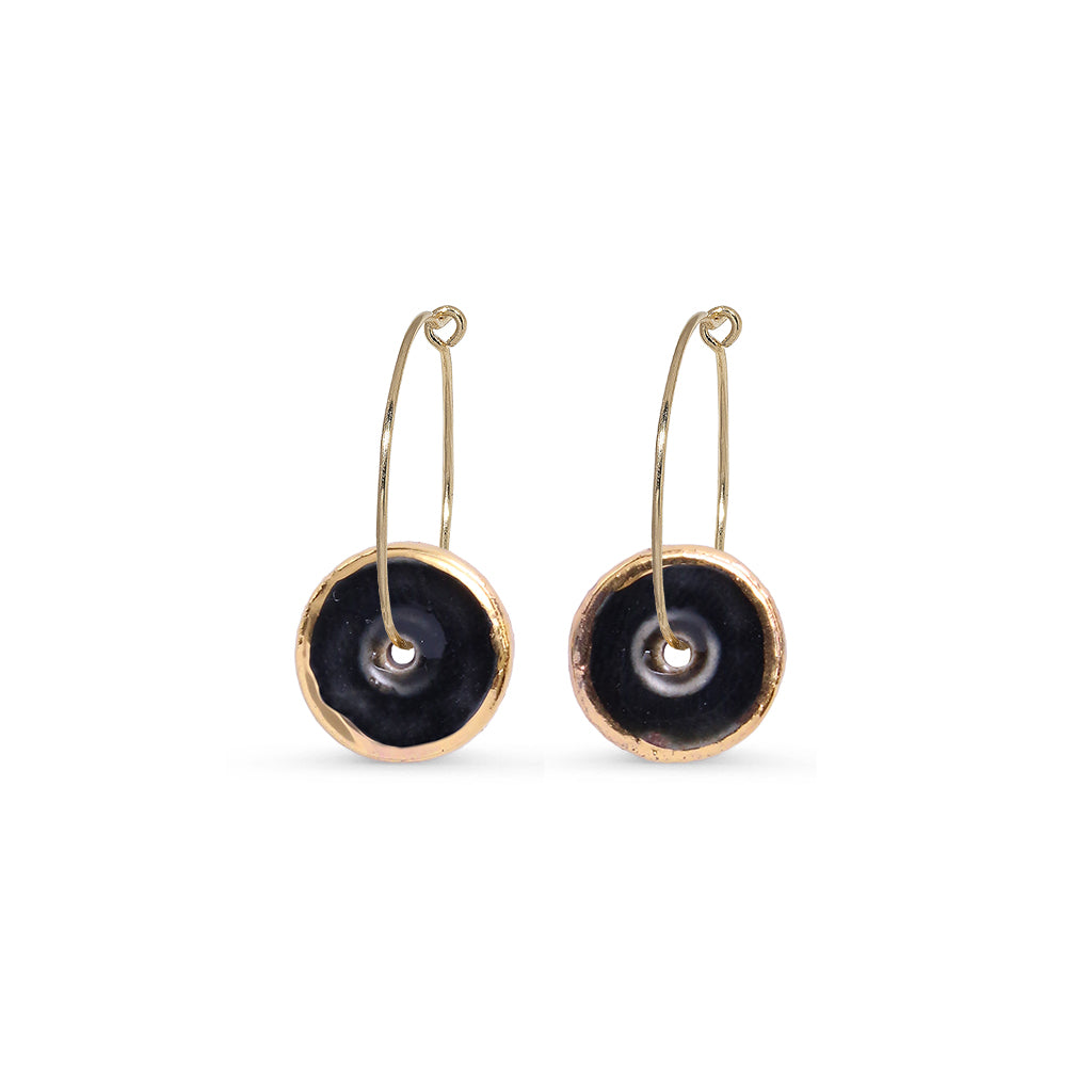 Pair of gold hoop earrings with black circular charms on a white background