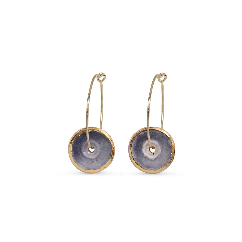 Pair of earrings with gold hoops and circular purple discs on a white background