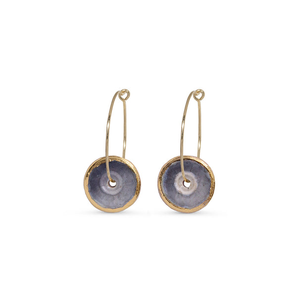 Pair of earrings with gold hoops and circular purple discs on a white background