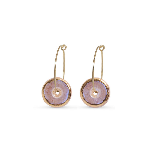 Pair of gold hoop earrings with round, pink glass centres on a white background