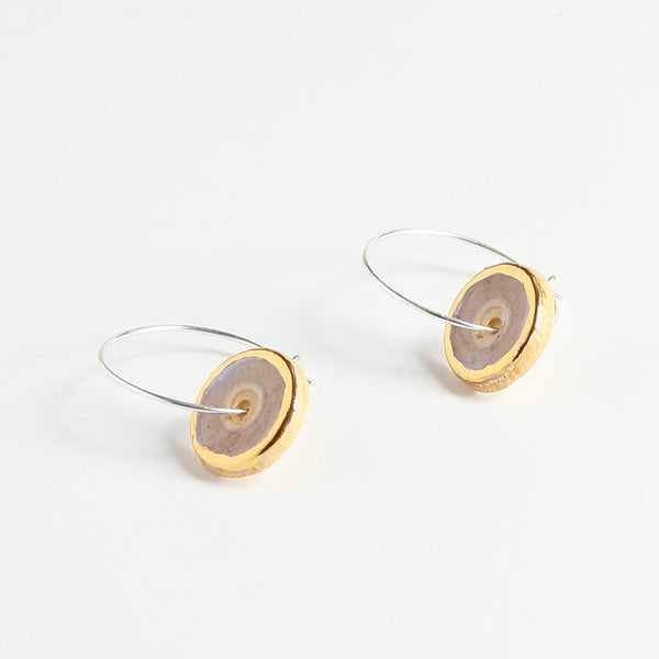 Pair of earrings with gold and pink circular designs on a white background