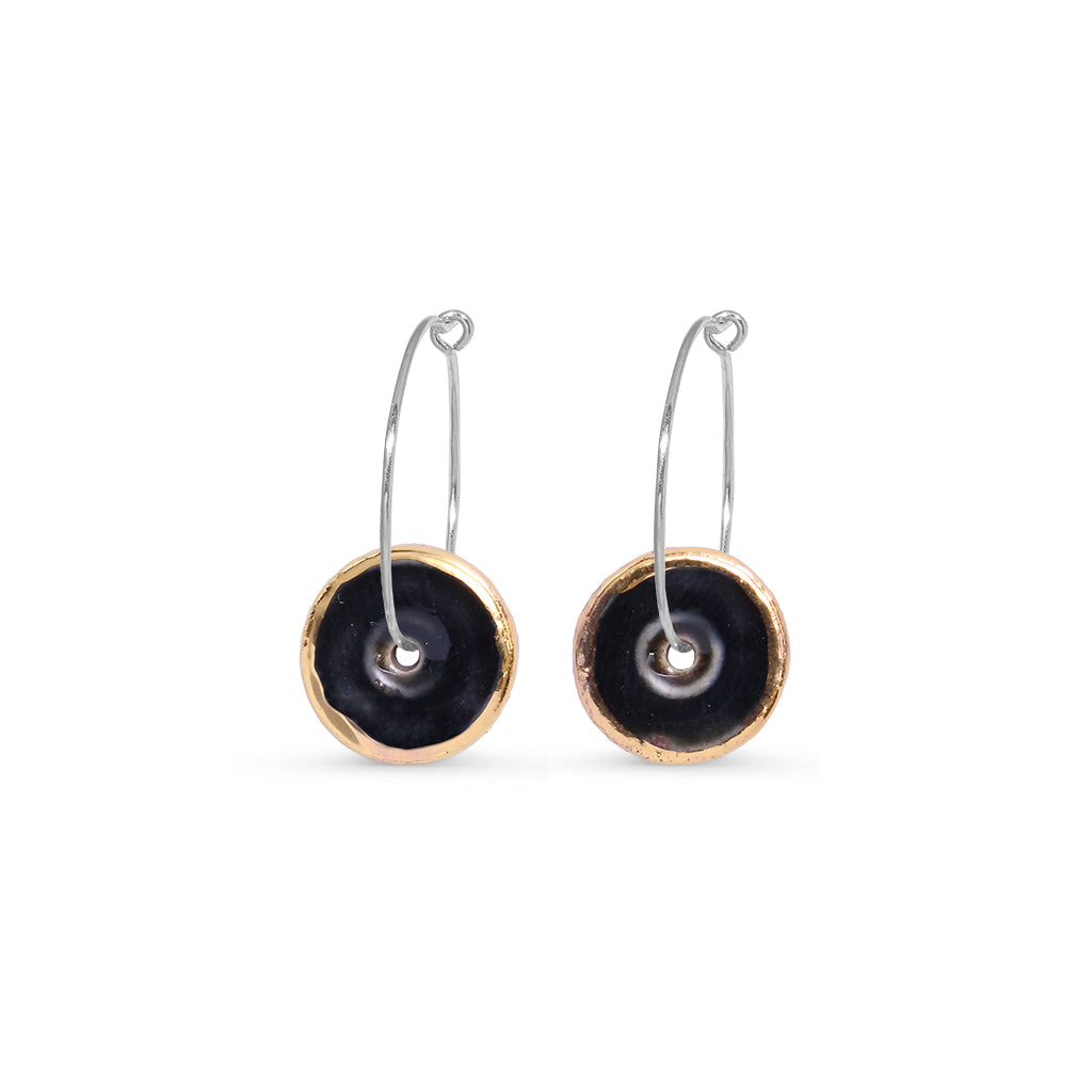 Pair of black circle earrings with gold lustre in circular designs on a white background