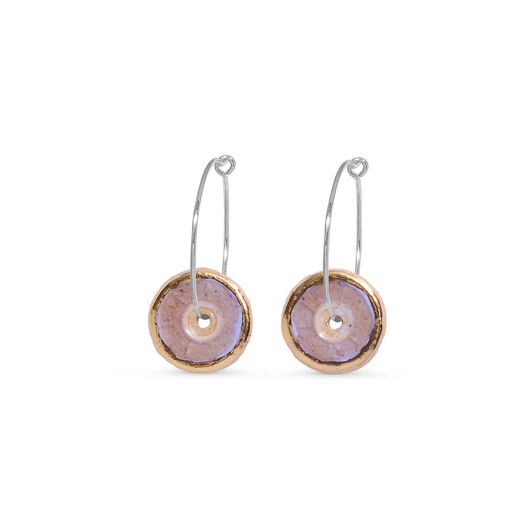 Pair of round earrings with gold, pink and silver accents on a white background