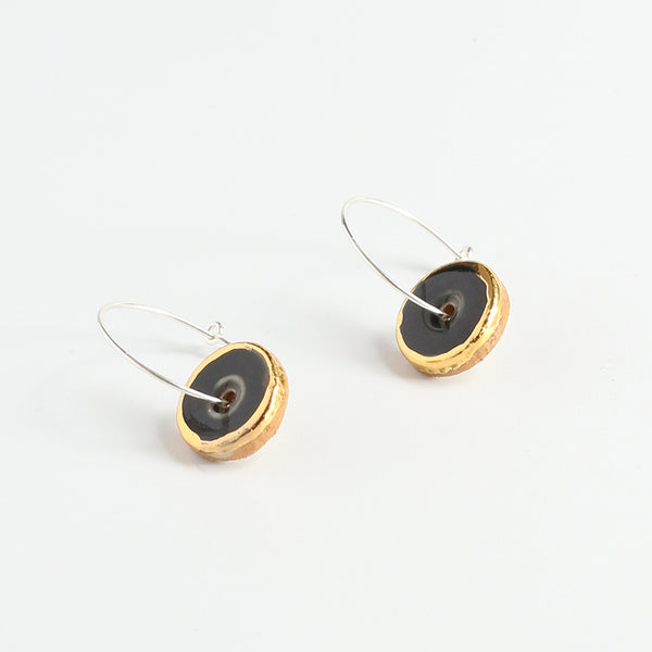 Pair of earrings with gold and black circular designs on a white background