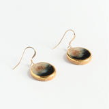Gold-framed earrings with round, textured stones on a white background