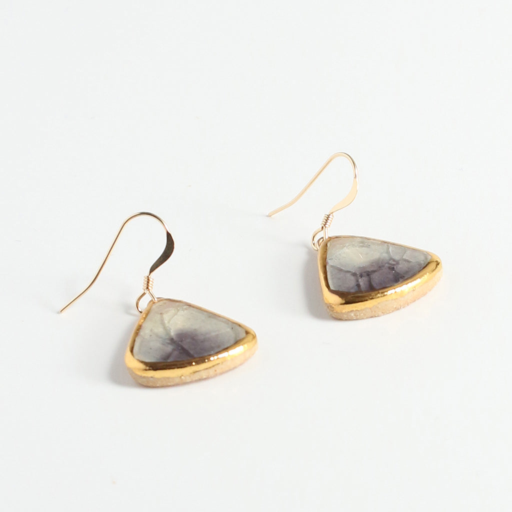 Gold-trimmed teardrop earrings on a light background