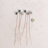 Close-up of pastel ceramic forget me not flower stems with copper wire stems on a table  – individually handcrafted floral home accessories from Habulous