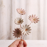A hand holding Handcrafted ceramic large pink and white  flower stems with soft glazes. Each flower features a flexible copper wire stem for easy adjustment.