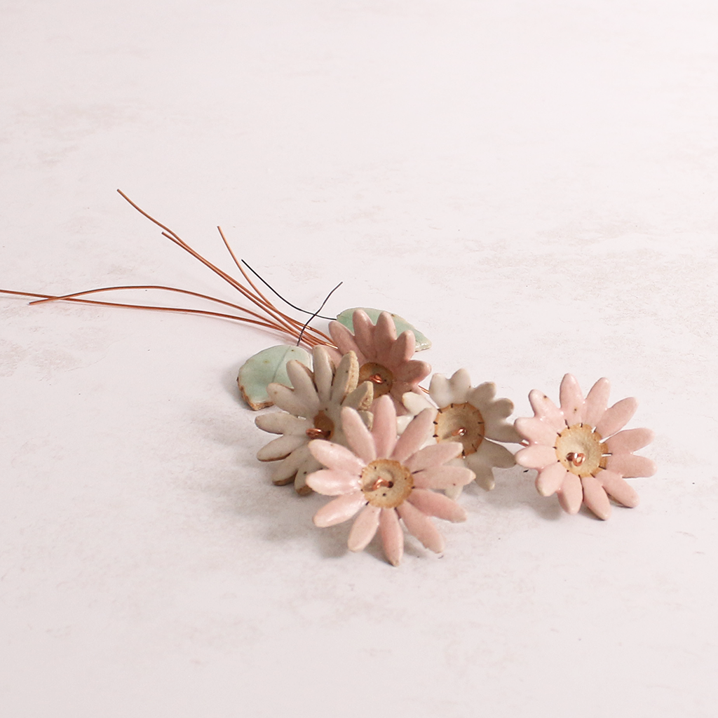Handcrafted ceramic large pink and white  flower stems with soft glazes displayed on a white table. Each flower features a flexible copper wire stem for easy adjustment.
