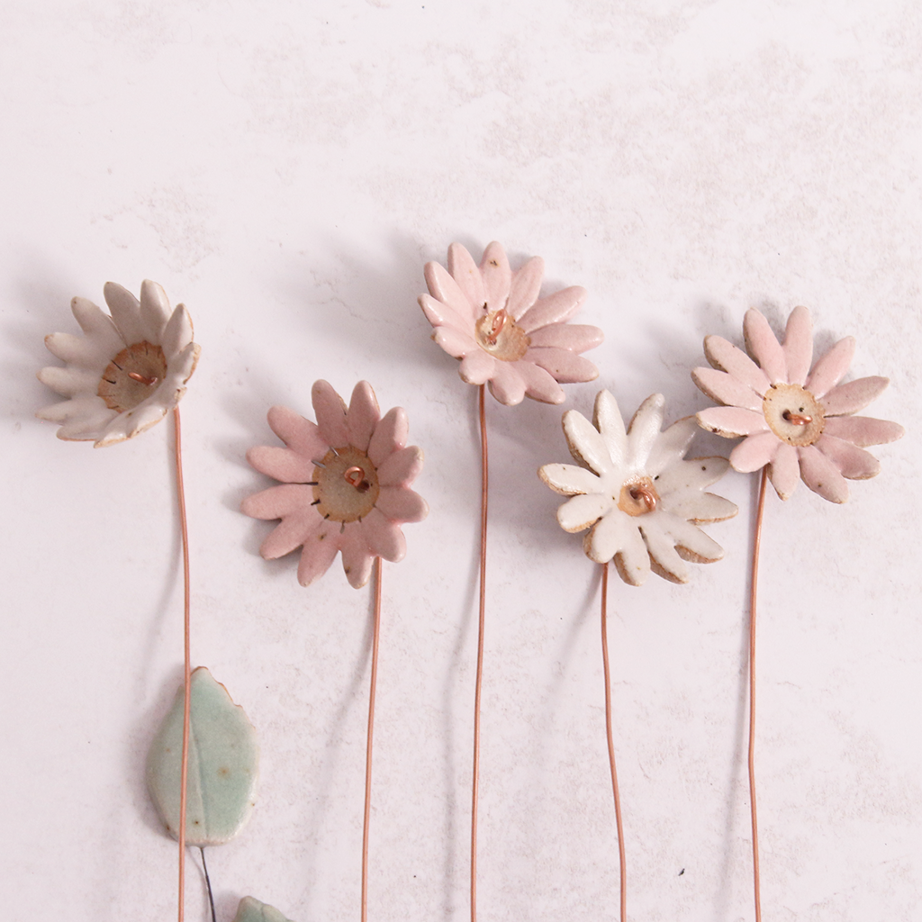 Handcrafted ceramic large pink and white  flower stems with soft glazes displayed on a white table. Each flower features a flexible copper wire stem for easy adjustment.