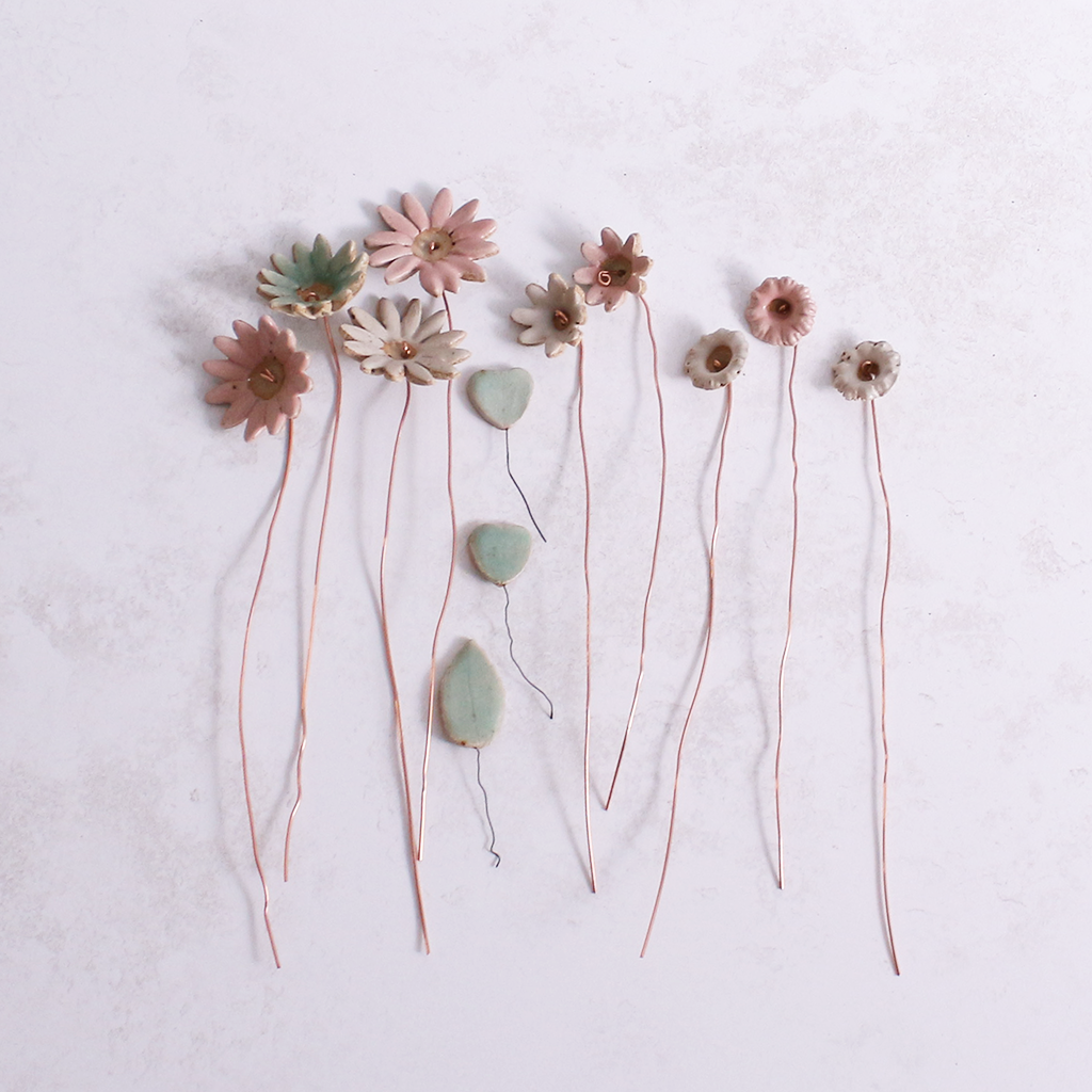 Handcrafted ceramic flower bouquet, featuring delicate pink and white wildflowers with green leaves, arranged with copper wire stems — perfect for rustic home decor.