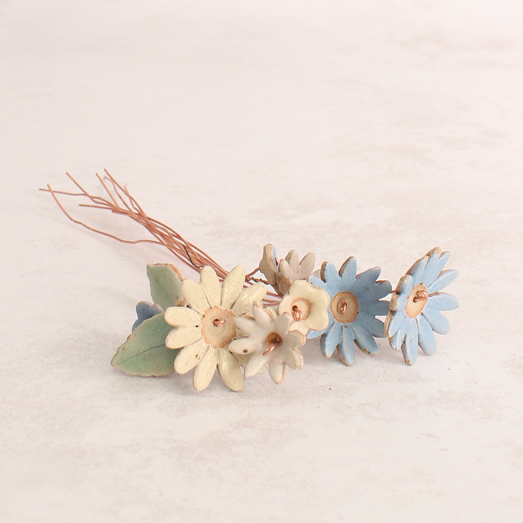 Handcrafted ceramic flower bouquet featuring delicate blue and white wildflowers with green leaves, arranged with copper wire stems — perfect for rustic home decor.