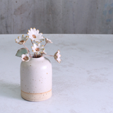 Small ceramic vase with decorative flowers on a light grey surface