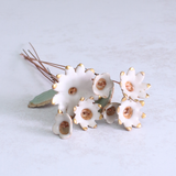 White ceramic flowers with gold accents on a light grey background