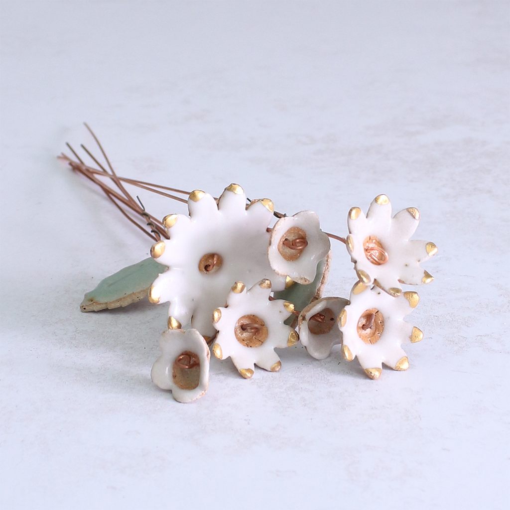 White ceramic flowers with gold accents on a light grey background