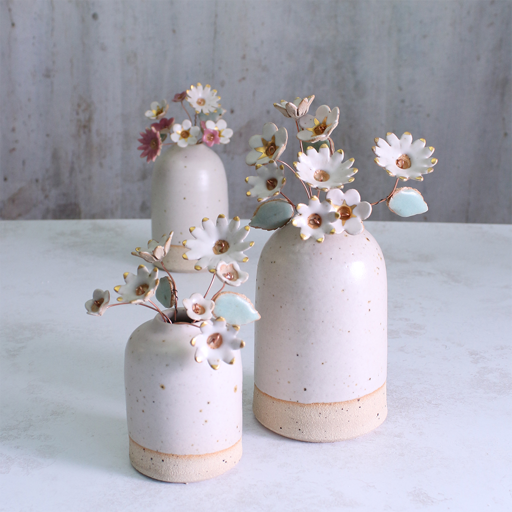 Handmade ceramic flower bouquet in white with gold-painted petals and copper wire stems displayed in a small ceramic vase.