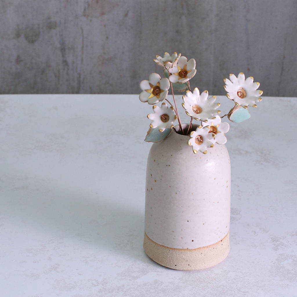 Handmade ceramic flower bouquet in white with gold-painted petals and copper wire stems displayed in a small ceramic vase.