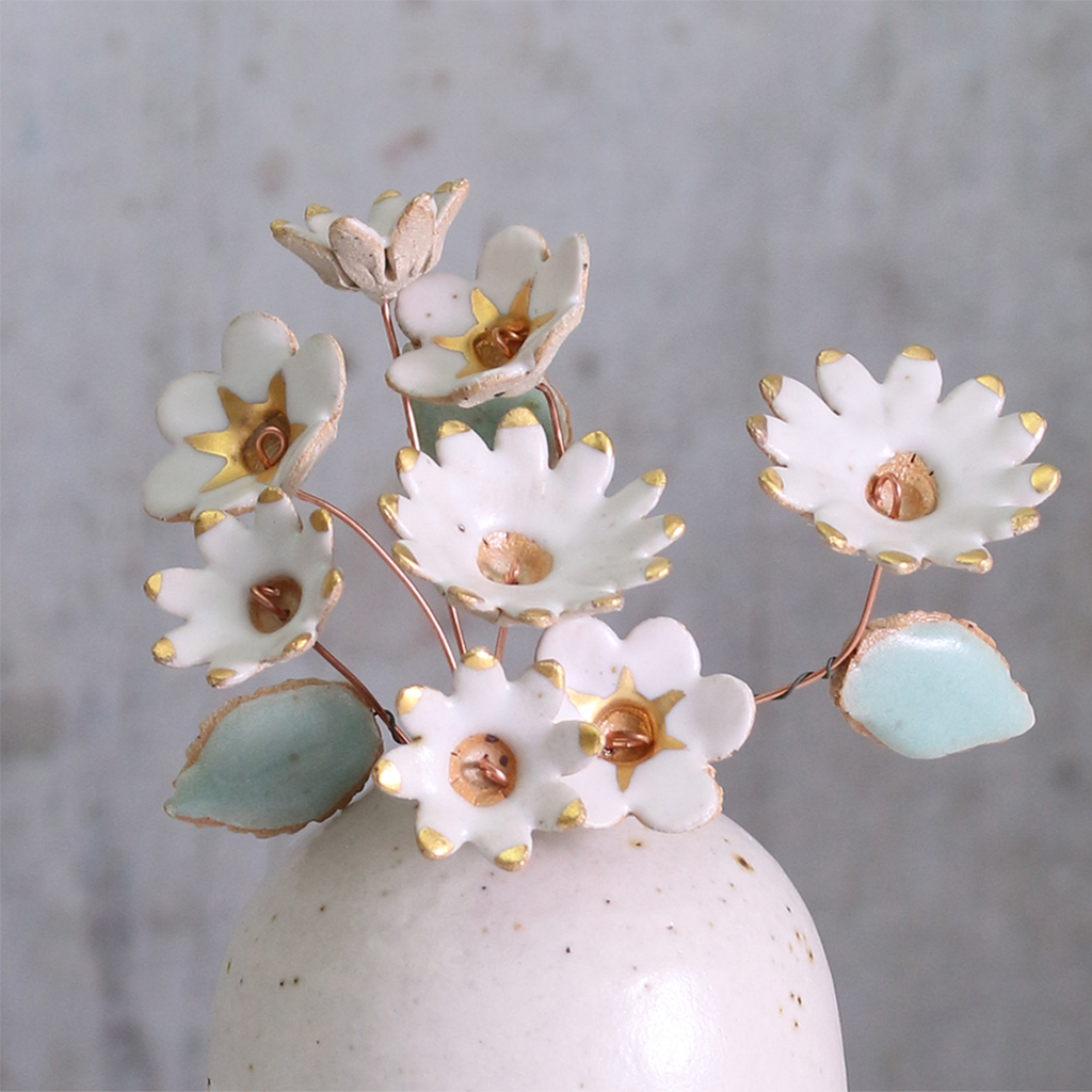 Handmade ceramic flower bouquet in white with gold-painted petals and copper wire stems displayed in a small ceramic vase.