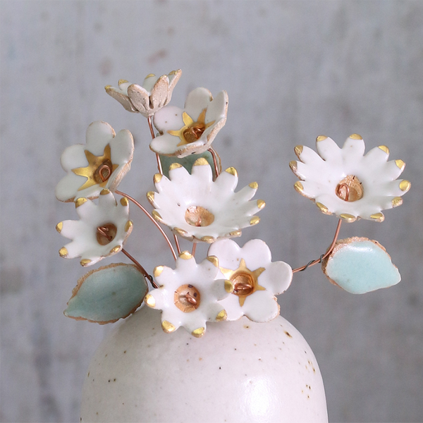 Handmade ceramic flower bouquet in white with gold-painted petals and copper wire stems displayed in a small ceramic vase.