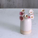 Handmade ceramic flower bouquet in white, pink, and fuchsia with gold-painted petals and copper wire stems displayed in a small ceramic vase.