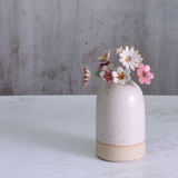 Handmade ceramic flower bouquet in white, pink, and fuchsia with gold-painted petals and copper wire stems displayed in a small ceramic vase.