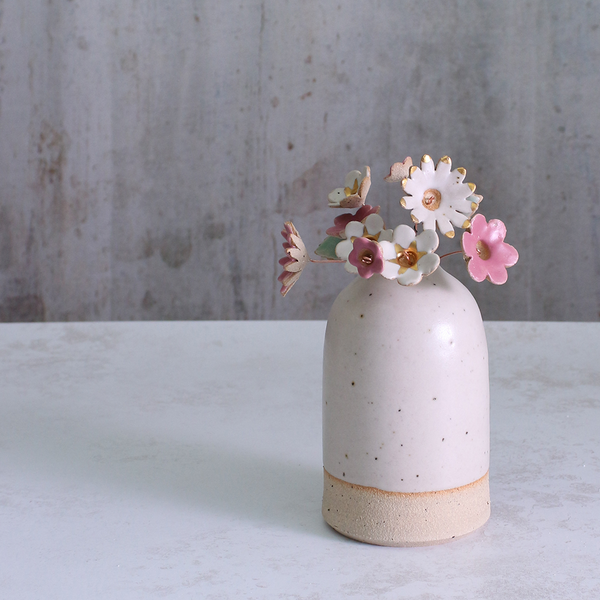 Handmade ceramic flower bouquet in white, pink, and fuchsia with gold-painted petals and copper wire stems displayed in a small ceramic vase.
